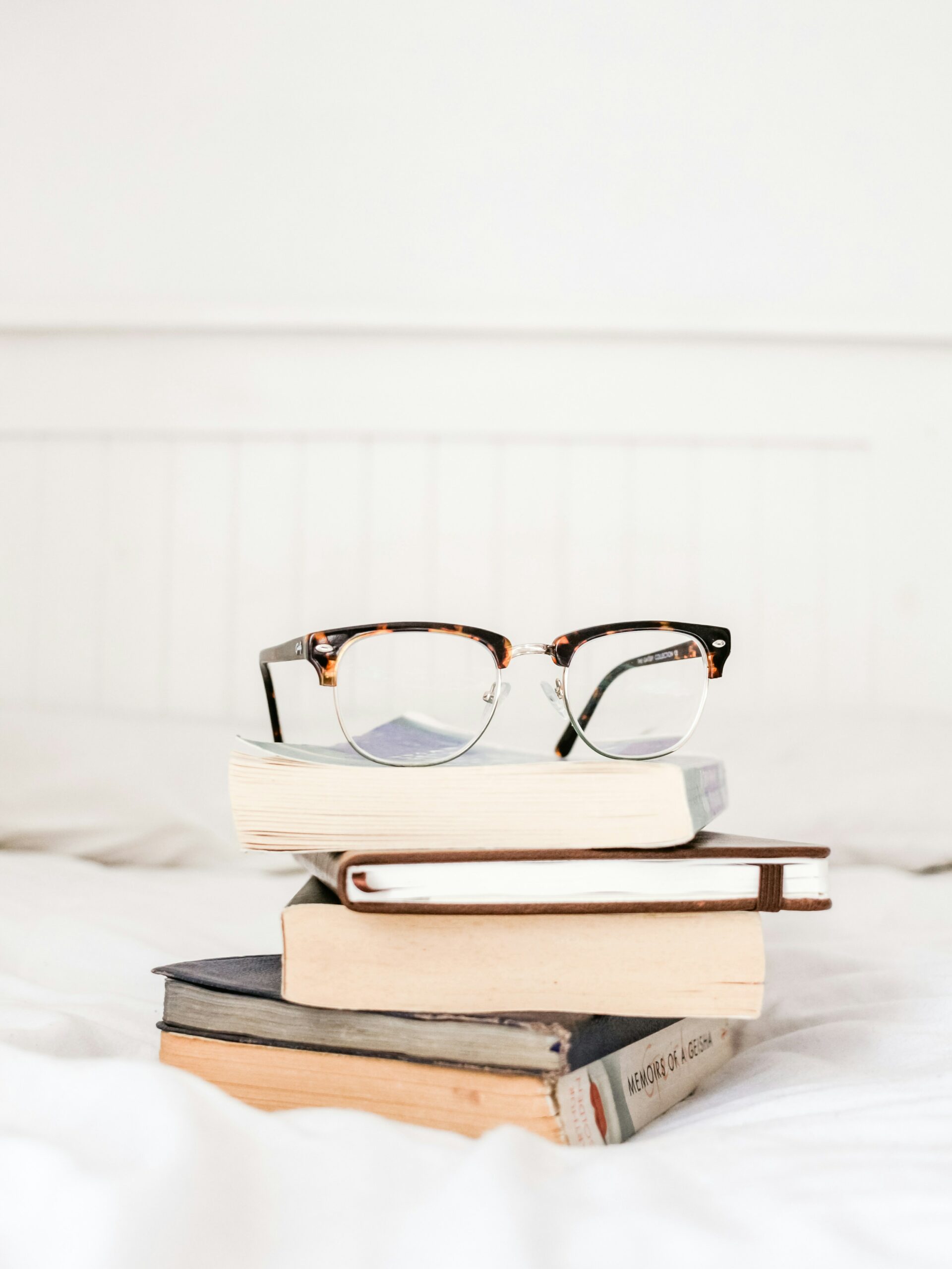 Stack of books with a pair of glasses on top.